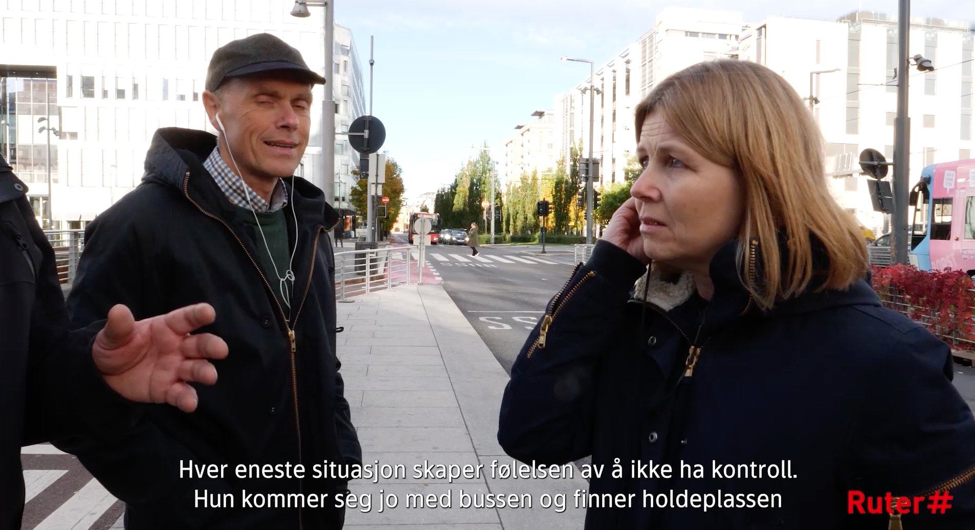 En mann og en kvinne deltar i en samtale på et busstopp i en moderne bysetting.